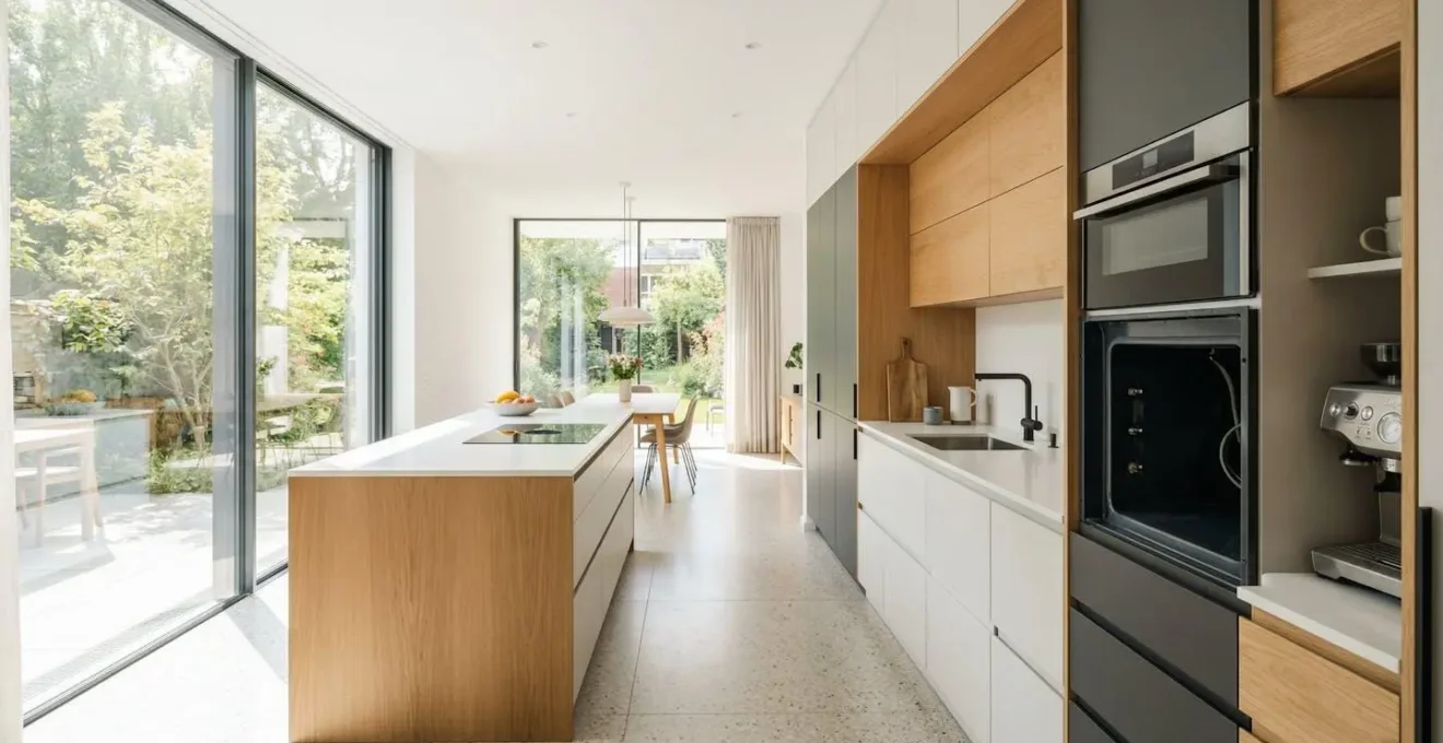 Cuisine contemporaine européenne avec emplacement four encastrable vide, meuble prêt à accueillir l'appareil, lumière naturelle abondante